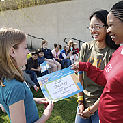 adults handing girl a certificate of excellence